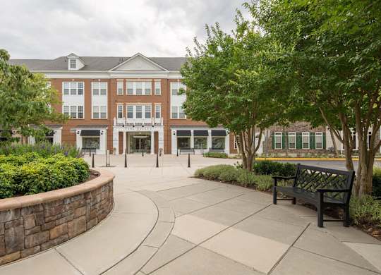 A brick building with a stone wall and a bench in front.