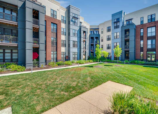 A row of modern apartment buildings with a green lawn in front.