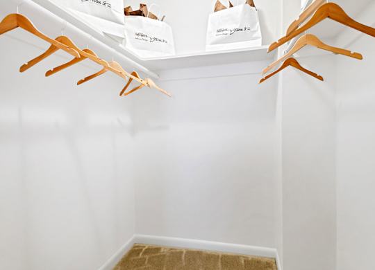 a walk in closet with shoe racks and bags on the wall