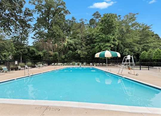 a swimming pool with a green and white umbrella and chairs around it