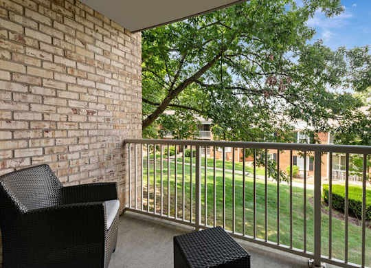 a balcony with two chairs and a tree in the yard