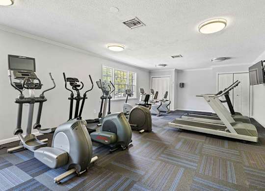 A gym with various exercise machines and a tv