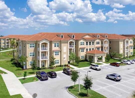 an image of an apartment complex with cars parked in a parking lot