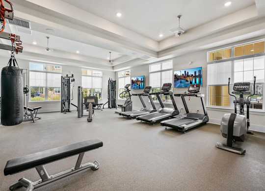 A spacious gym with treadmills, a punching bag, and a bench.
