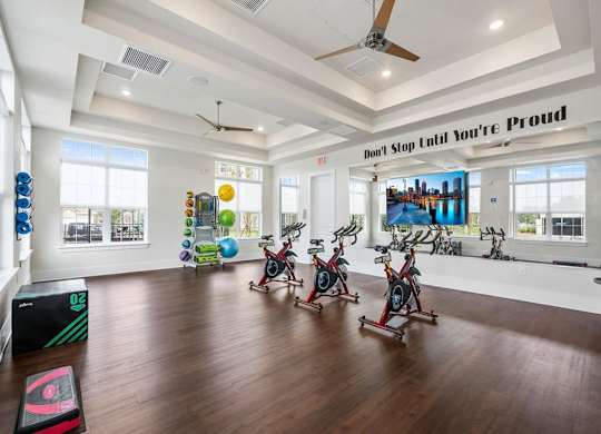 A gym with a row of stationary bikes and a motivational sign on the wall.