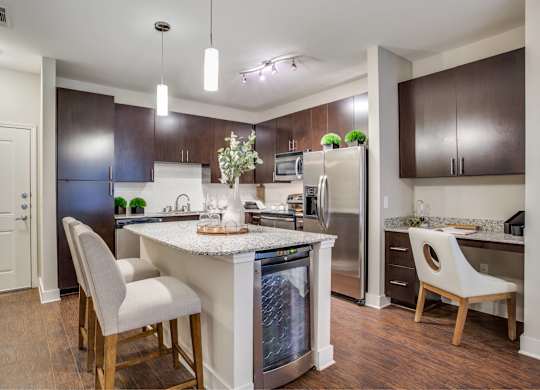 Kitchen with island, granite countertops, dark wood cabinetry, and stainless steel appliances