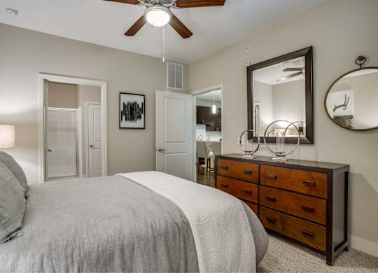 A bedroom with a large bed, a dresser, and a mirror.