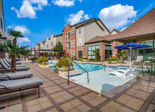 A pool surrounded by lounge chairs and umbrellas.