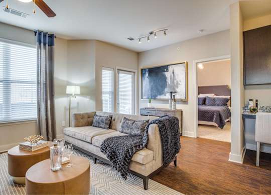 A well-lit, spacious living room with a couch, a bed, and a ceiling fan.