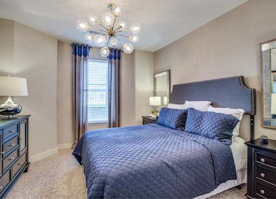 A bedroom with a large bed and a chandelier.