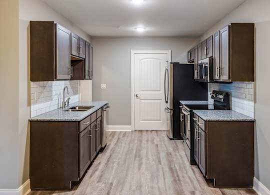A kitchen with dark brown cabinets and a black refrigerator at Mode at Melbourne, LLC Apartments, Florida, 32901