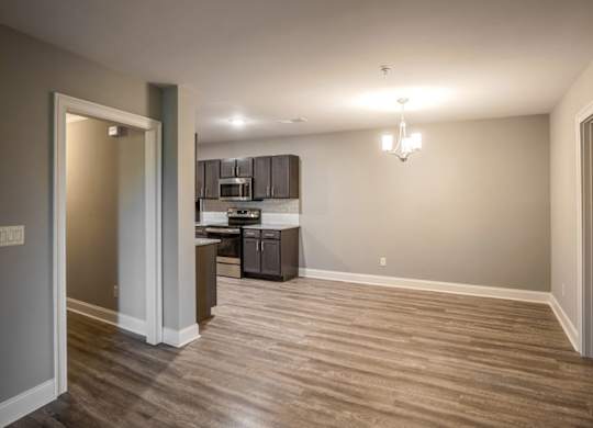 A kitchen with a refrigerator, microwave, and oven is visible through a glass door at Mode at Melbourne, LLC Apartments, Melbourne, FL, 32901