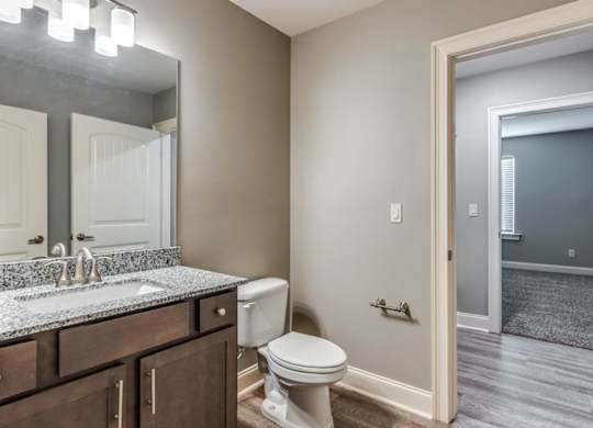 A bathroom with a toilet, sink, and mirror at Mode at Melbourne, LLC Apartments, Florida