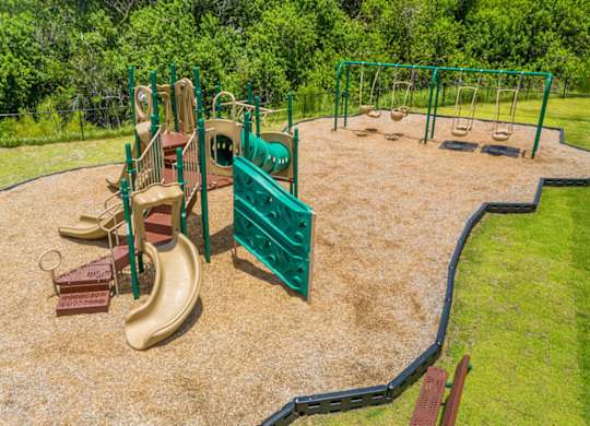 A playground with a green fence and a yellow slide at Mode at Melbourne, LLC Apartments, Florida, 32901