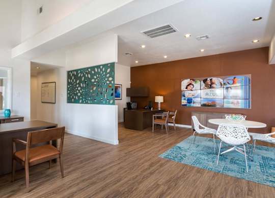 A modern living room with a brown wooden floor and white furniture.