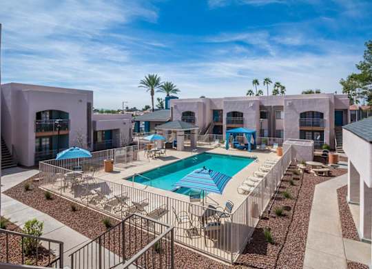 A pool surrounded by a fence and chairs.