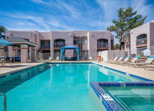 A swimming pool in front of a building with a blue sky in the background.