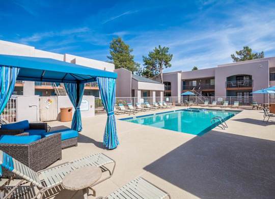 A pool area with a blue canopy and lounge chairs.