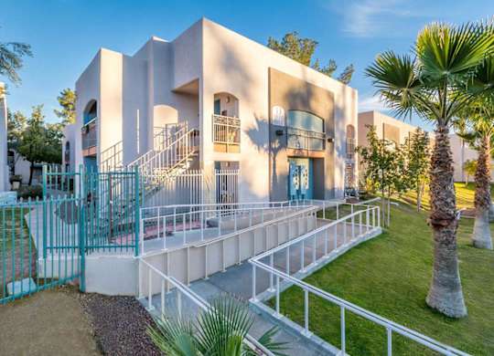 A modern building with a white exterior and a blue gate.