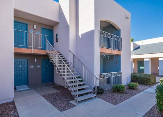 A building with a blue door and a staircase leading to a balcony.