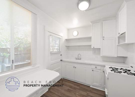 A kitchen with white cabinets and a stove top oven.