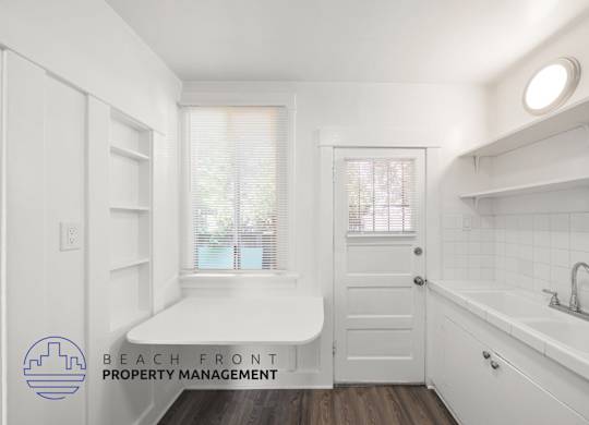 A white bathroom with a window and a sink.