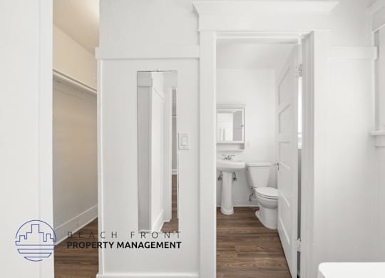 A white bathroom with a toilet, sink, and mirror.