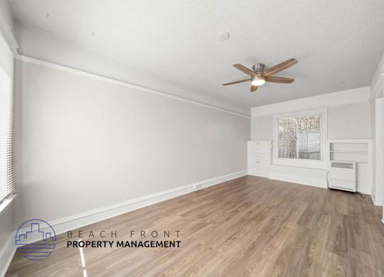 A room with a ceiling fan and wooden flooring.