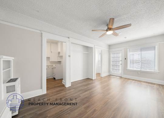 A spacious room with a ceiling fan and wooden flooring.