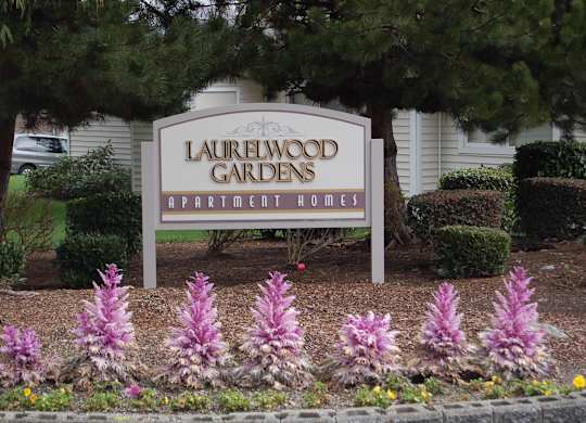 A sign for Laurelwood Gardens Apartment Homes is in front of a building.