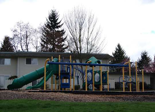 A playground with a green slide and a blue and yellow structure.