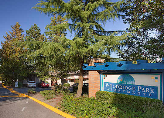 A sign for Woodridge Park Apartments is on the side of a street.