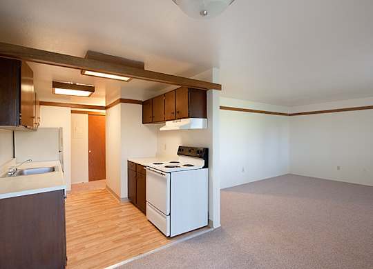 A kitchen with a white stove and wooden floors.