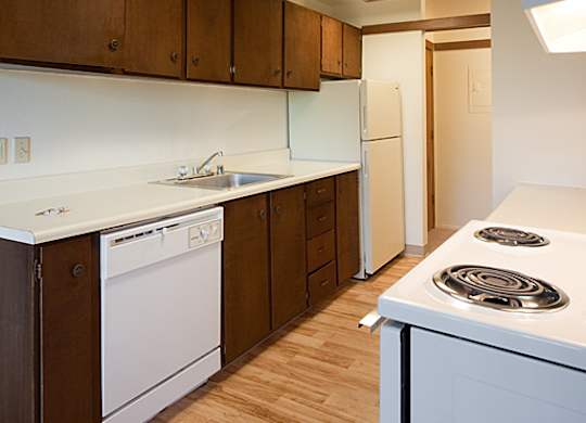 A kitchen with white appliances and wooden cabinets.