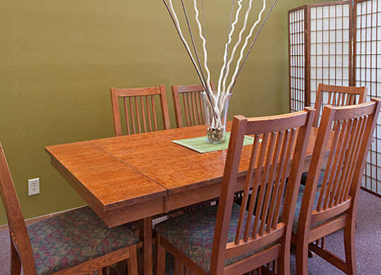 A wooden table with chairs and a vase with branches in it.
