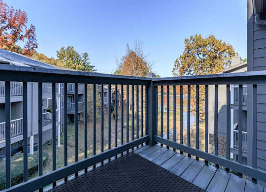 A balcony with a black railing and a black mat on the floor.