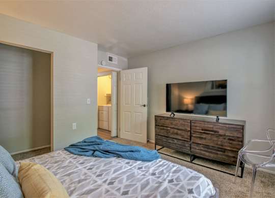 A bedroom with a bed, a chair, and a television.