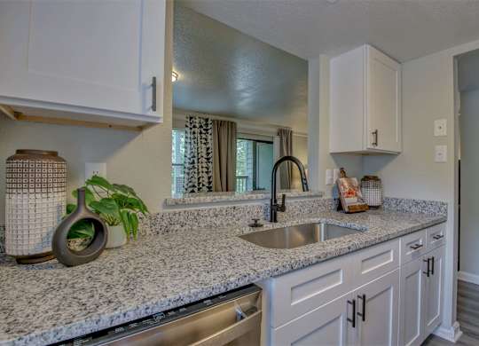 A kitchen with a granite countertop and white cabinets.