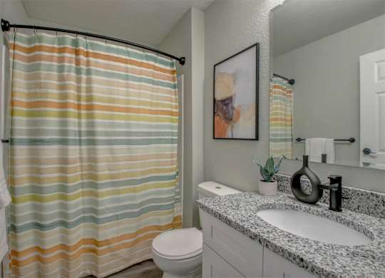 A bathroom with a striped shower curtain and a white toilet.
