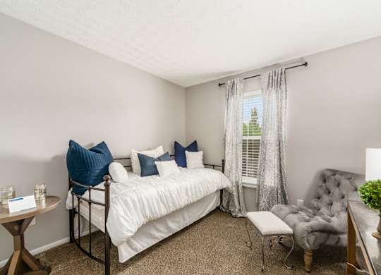 A bedroom with a bed, chair, and window.