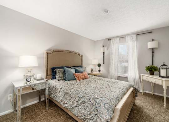 A bedroom with a bed, nightstands, and a window.