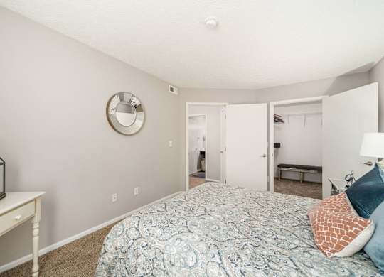 A bedroom with a bed, a mirror, and a lantern on a table.