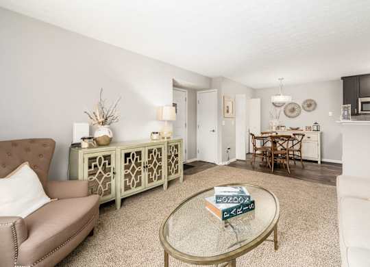 A living room with a sofa, a coffee table, and a dining area in the background.