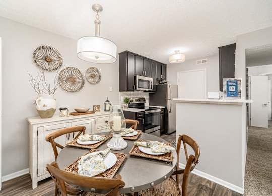 A dining table with chairs and a decorative wall hanging above it.