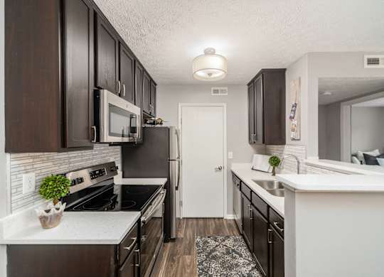 A kitchen with dark brown cabinets and white countertops.