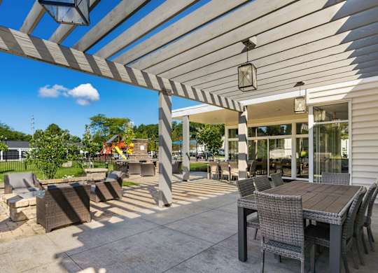 A patio with a table and chairs under a striped awning.