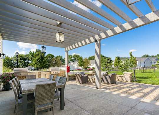 A patio with a table and chairs under a white pergola.