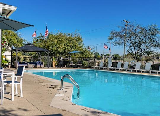A pool with a slide and chairs around it.