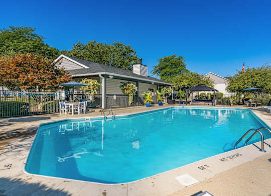 A large outdoor swimming pool with a pavilion and lounge chairs.