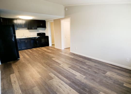 an empty kitchen and living room with wood flooring in an apartment